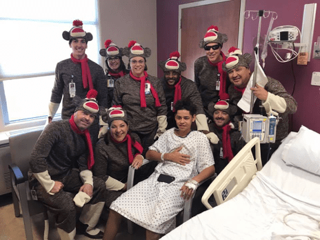 employees dressed as sock monkeys for halloween pose for photo with child patient